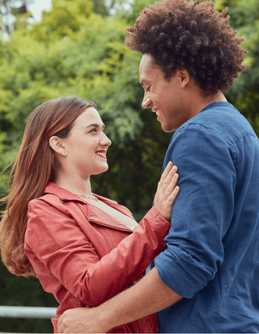 A smiling couple holding each other with trees in the background