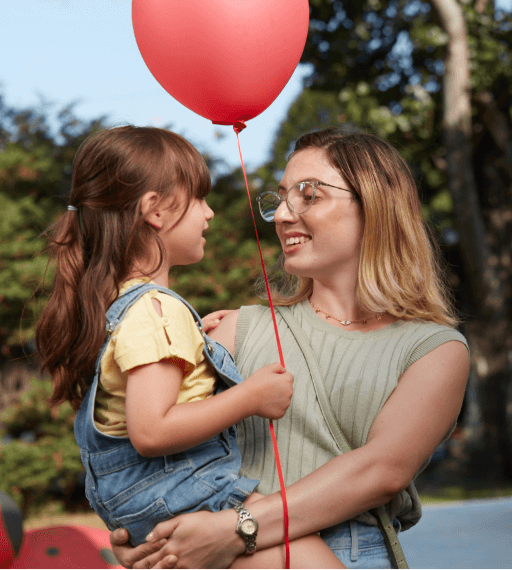 A mother holding her child with red balloon in her hand. 